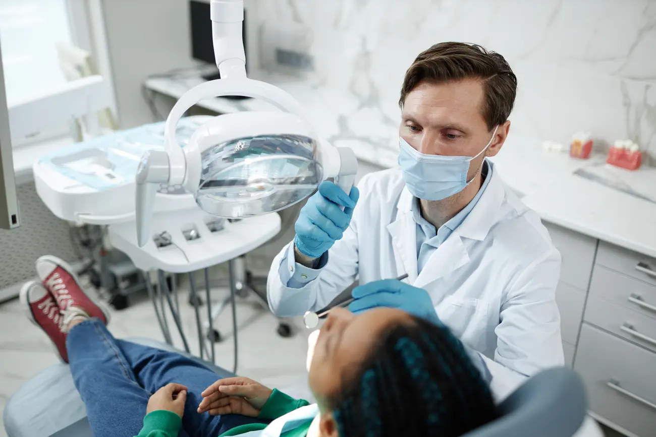 male dentist wearing mask during child checkup in 2023 11 27 05 00 20 utc